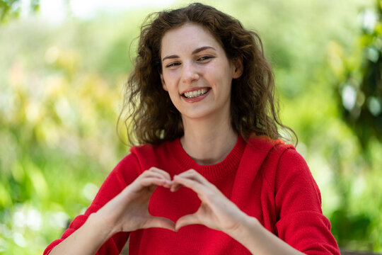 Smiling young woman making heart shape with hands