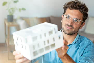 Male entrepreneur with eyeglasses holding architectural model in office