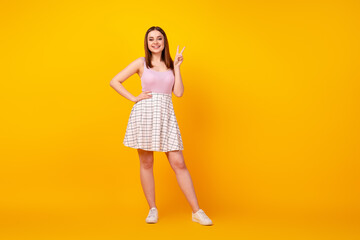 Full size photo of pretty girl show fingers peace cool v-symbol youngster isolated over yellow color background