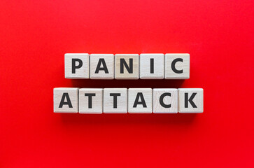 Obraz premium Text PANIC ATTACK on wooden cubes. Mental health, disorder. Flat lay, top view on red background.&nbsp;