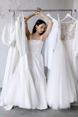 Young beauiful happy bride wearing white wedding dress and posing in bright empty interior