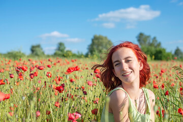 Teenage girl smiling in poppy field during sunny day