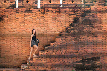 Attractive asian woman walking up the brick wall stairs in Tha Phae Gate at Chiang Mai