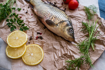 Fresh raw whole fish of mirror carp with spices, lemon and herbs on a background of craft paper