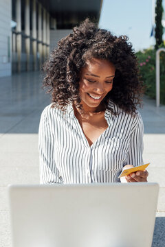 Happy Young Businesswoman Using Laptop Doing Online Shopping Outside Office Building