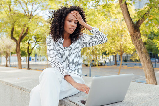 Worried businesswoman sitting with laptop at office park