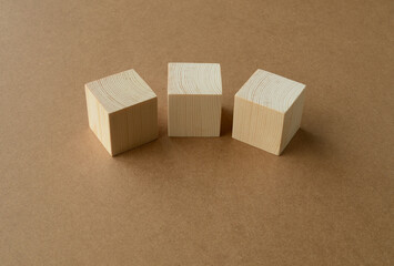 Three wooden cubes. Blank wooden cubes on a cardboard background. Arrangement of blank wooden cubes