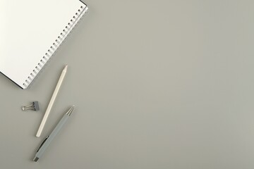 Minimal workspace flat lay, grey background, spiral notebook, pen, pencil, space for text, product or design, modern work desk, business, writing, planning concept.