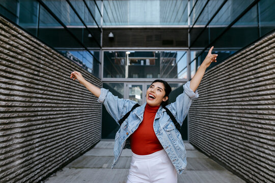 Cheerful woman looking away while dancing with arms outstretched
