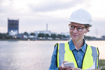 Smiling female blue-collar worker looking away holding smart phone