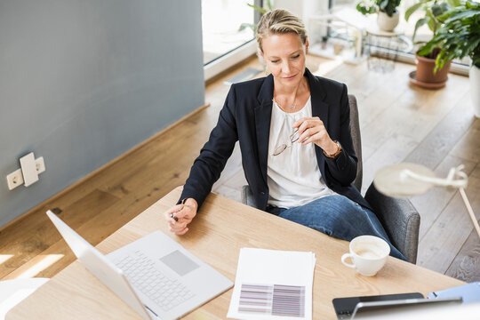Businesswoman with laptop and digital tablet sitting at office