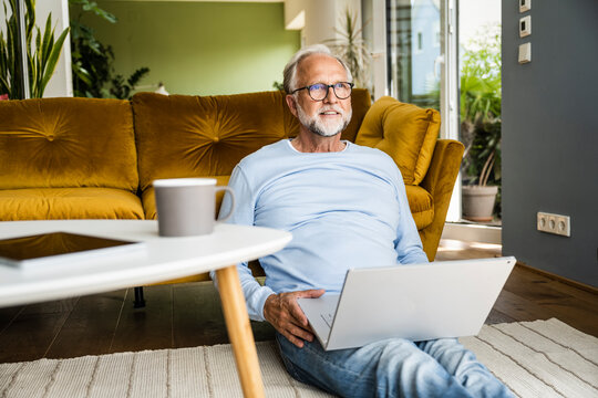 Mature man with laptop sitting on floor at home