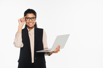 Smiling african american businesswoman in eyeglasses holding laptop isolated on white.