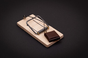 Temptation by Sweets or Chocolate Addiction - Sweet Wedge of Milk Chocolate in Wooden Mousetrap on...
