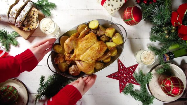 Woman set festive Christmas dinner table with traditional foods and dished &ndash; baked ham, chicken, roasted carrots and brussels sprouts, potato, with Xmas decor and gifts. Preparation fod Christmas dinn