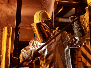 Male worker holding metal rod in foundry