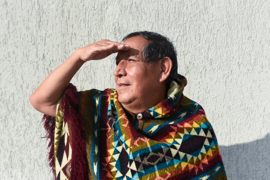 Senior man shielding eyes with hand while looking away on sunny day