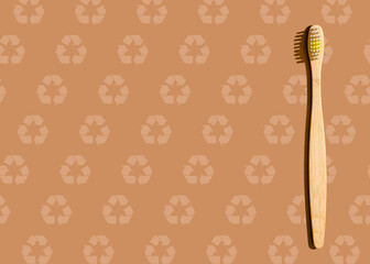 Studio shot of wooden toothbrush lying against brown pattern with recycling symbols