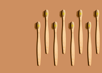 Pattern of wooden toothbrushes flat laid against brown background