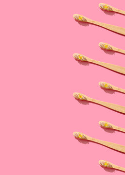 Pattern of wooden toothbrushes flat laid against pink background