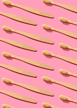 Pattern of wooden toothbrushes flat laid against pink background