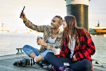 Friends taking selfie on smartphone on pier