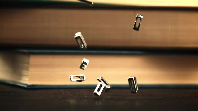 The metal letters of the English alphabet fall on the table. On a black background. Filmed is slow motion 1000 frames per second.