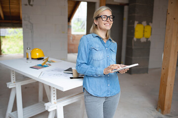 Female design professional with digital tablet standing in front of table