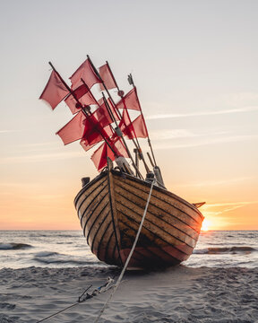 Lone fishing boat left on sandy shore at sunset