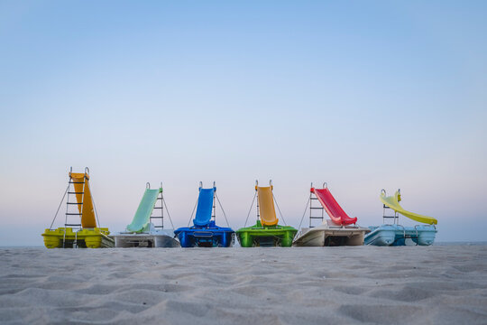 Clear sky over row of pedal boats left on sandy beach at dusk