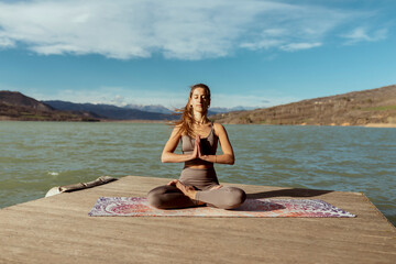 Young woman with hands clasped meditating on sunny day