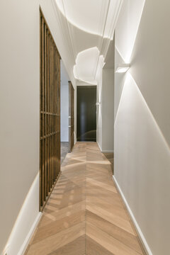 Narrow corridor with parqueted floor and gray walls