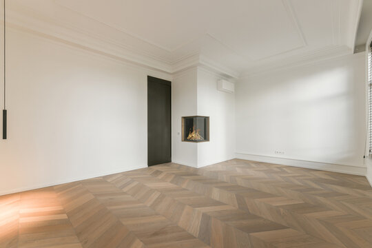 Spacious empty living room with parquet and artificial fireplace