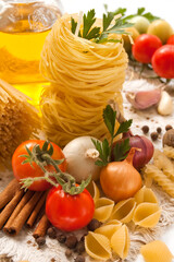 Pasta, vegetables, spices and oil on the table for Italian food