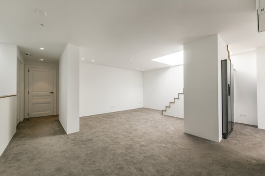 Empty basement space with white walls and concrete floor