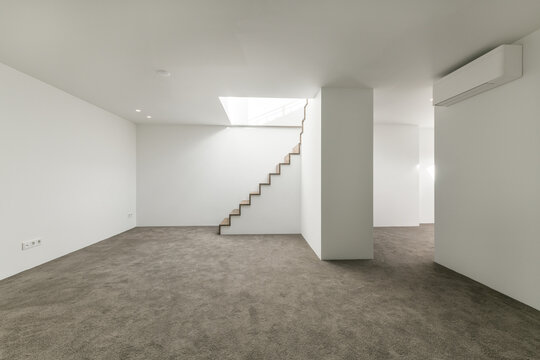 Empty basement space with white walls and concrete floor