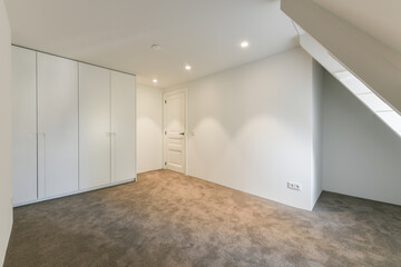 Interior of mansard room with built in white wardrobe