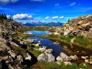 landscape of north cascade mountains with reflective lake, white clouds, and blue sky