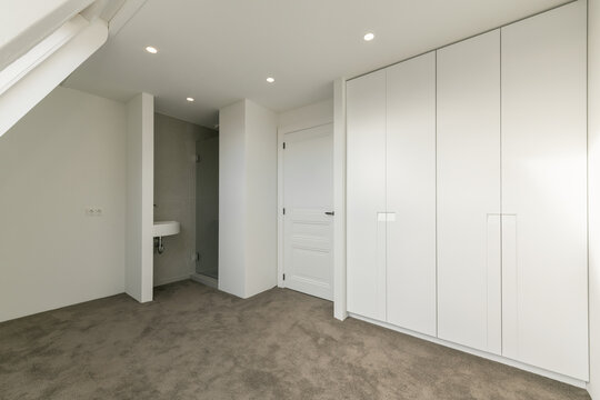 Interior of mansard bedroom with built in wardrobe and restroom
