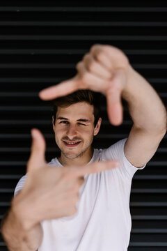 Man winking while making finger frame in front of shutter