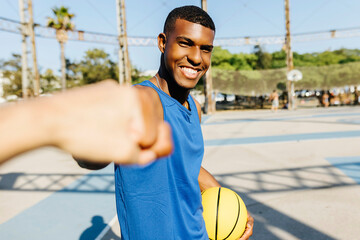 Smiling man giving fist bump to friend at sports court