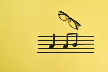 Fototapeta na wymiar A pair of eyeglasses and musical notes on a yellow background