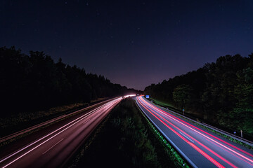 A german Autobahn at night with lighttrails of the fast driving cars in red, wallpaper photo for a...
