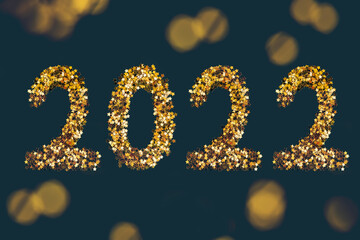 Golden stars sparkles shaped 2022 year on dark background.