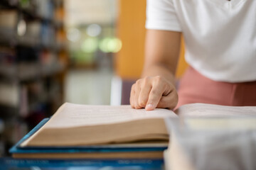 Young Asian women are searching for books and reading books on the tables and aisles of the college libraries to research and develop their academic and education self