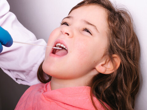 Crop nurse taking sample of saliva of girl