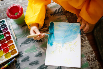 cute caucasian child Toddler is engaged in creativity in a yellow protective apron, the child draws with paints on salt, unusual drawing and developmental activities