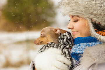 Woman hug warming her little dog in winter