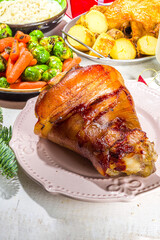 Festive Christmas dinner table with traditional foods and dished – baked ham, chicken, roasted carrots and brussels sprouts, potato, with Christmas decor and gifts 