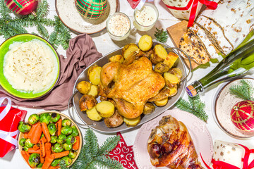 Festive Christmas dinner table with traditional foods and dished – baked ham, chicken, roasted carrots and brussels sprouts, potato, with Christmas decor and gifts 